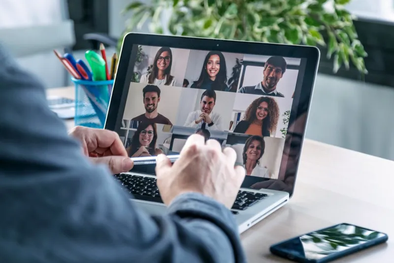 back view of male employee speaking on video call with diverse colleagues on online briefing with laptop at home