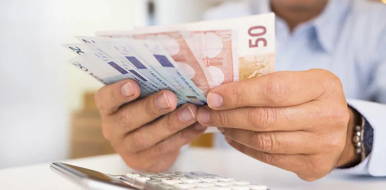 a man counting paper bills with a calculator