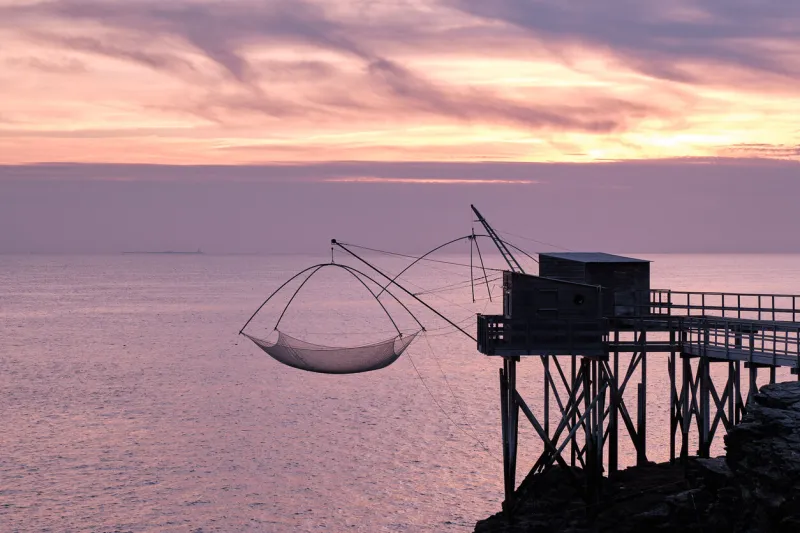 the fishing huts with nets on the atlantic ocean coast near pornic in france during the sunset