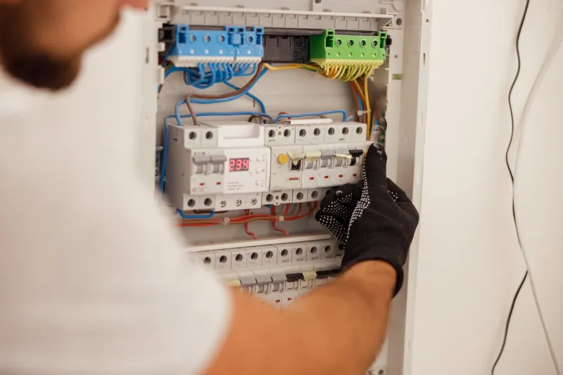 hand of electrical technician working with fuses at the circuit breaker control cabinet on the wall manual work, maintenance, repair service concept