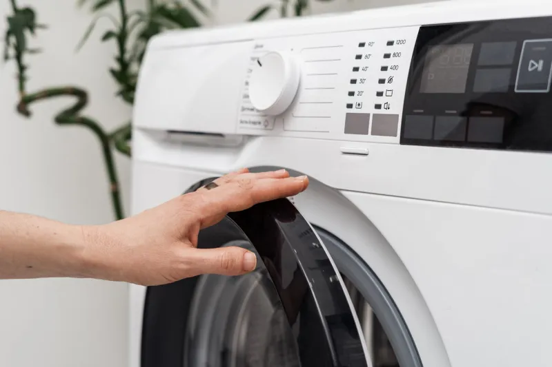 cropped view of woman open or close door at automatic washing machine with settings on digital display and modern control panel laundry at home and daily housework routine concept