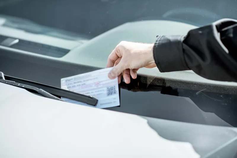 policeman putting fine for improper parking on the windshield of the car, close-up view