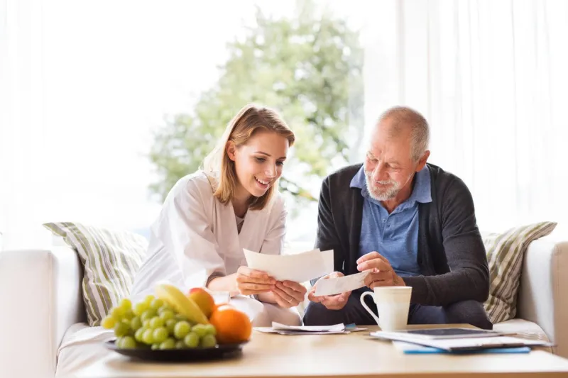 health visitor and a senior man during home visit a female nurse or a doctor discussing test results