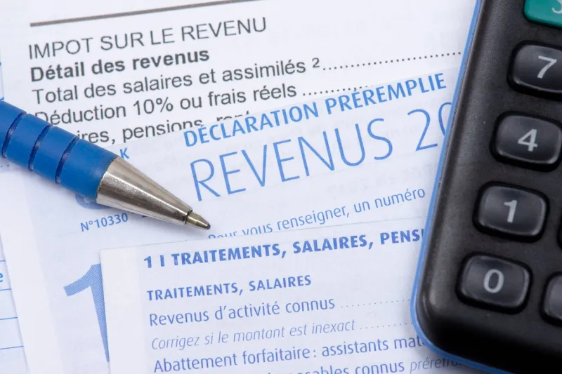 french pre-filled income tax return with the page about income from salaries, treatments, pensions and annuities, along with a pen and a calculator
