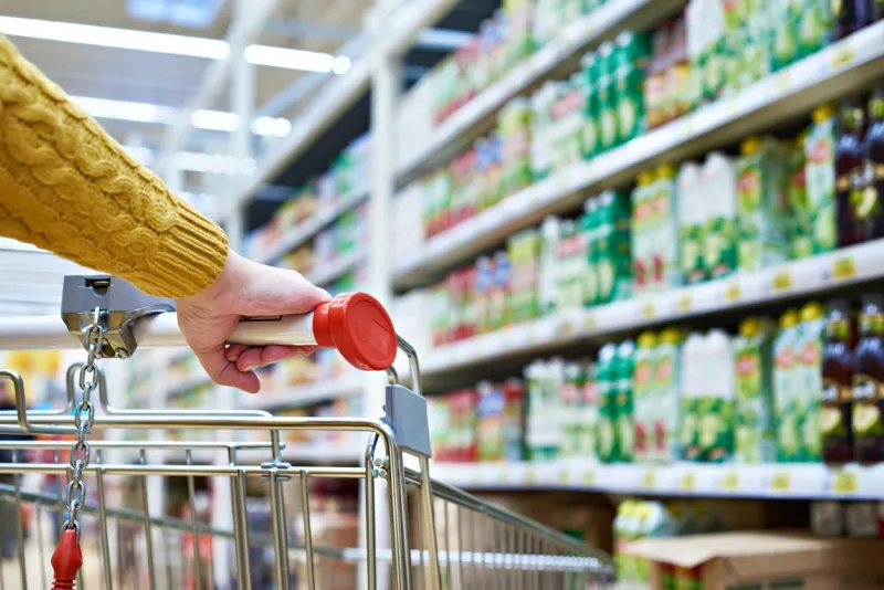 buyers hand on shopping cart in store shelves