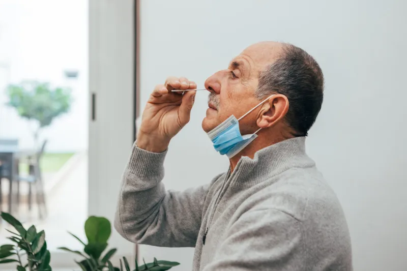 senior man sitting, self test for covid-19 at home with antigen test kit coronavirus nasal swab test for infection medicine and health-related services online