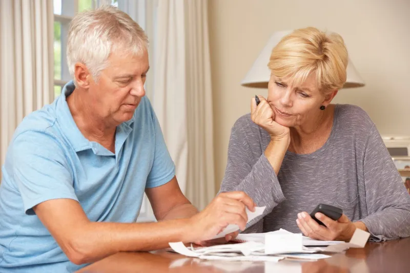 worried mature couple checking finances and going through bills together looking concerned
