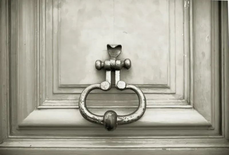 old wooden door with metal handle knocker in paris, france antique wooden door of apartment building, outdoor horizontal image