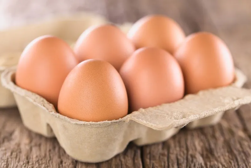 raw brown eggs in egg box or carton (very shallow depth of field, focus on the front of the first egg)
