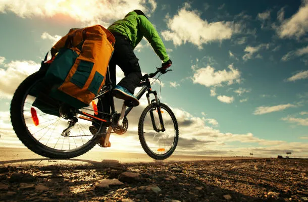 cyclotouriste avec vélo chargé à cheval sur une route vide