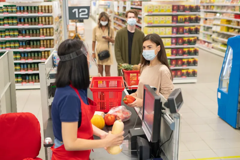customers in supermarket checkout queue wearing masks and following social distancing rule during covid-19 quarantine time