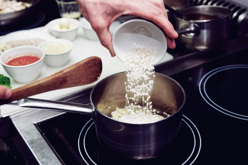 chef is pouring rice in stewpan, toned image
