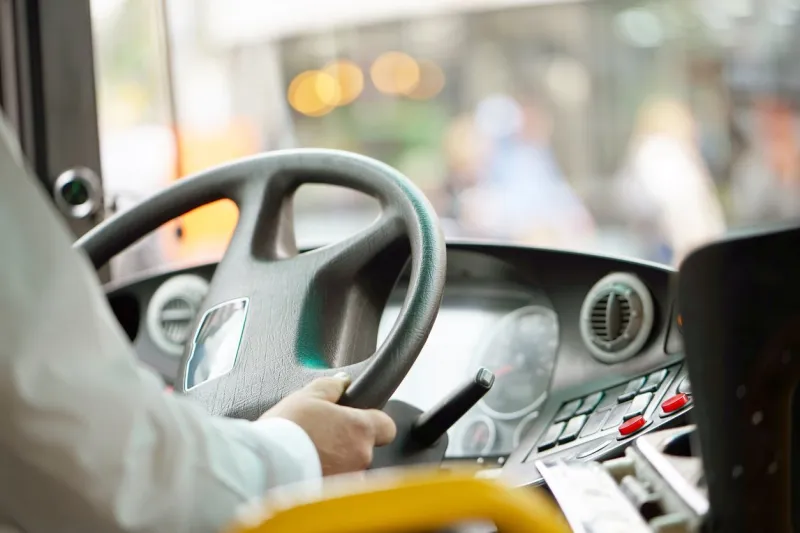 hands of driver in a modern bus by drivingconcept - close-up of bus driver steering wheel and driving passenger bus