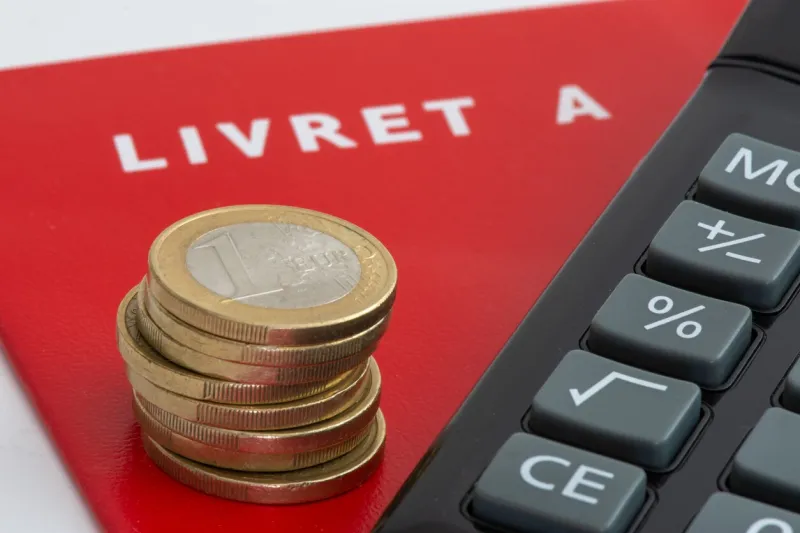 france  livret a savings book with a stack of euro coins and a calculator the livret a is a regulated french savings account whose interest rate and deposit limit are defined by the government