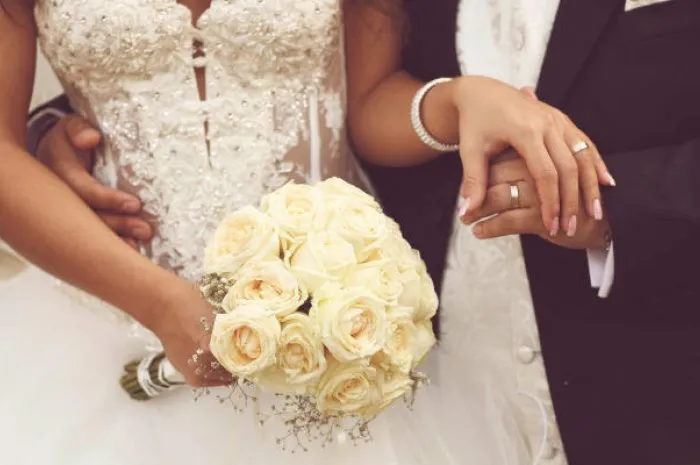 détail du bouquet de roses de la mariée et les mains tenant