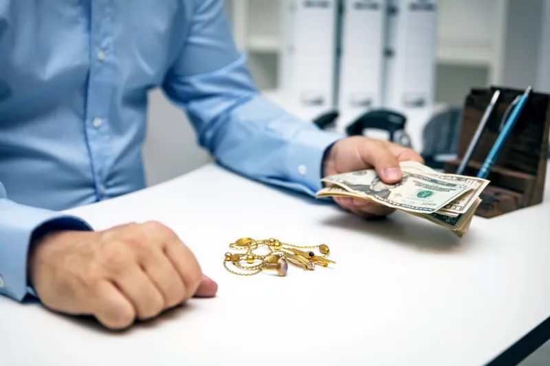 man buying gold jewellry, pawn shop and us dollar banknotes