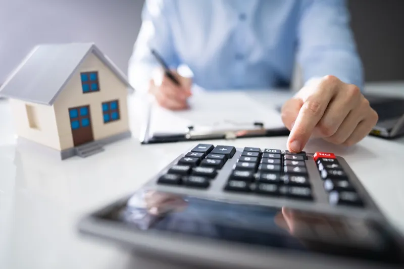 close-up of a person hand calculating a real estate property tax on wooden desk