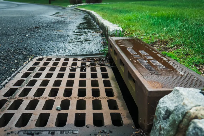 a storm drain on the side of a road reads dump no waste drains to waterways