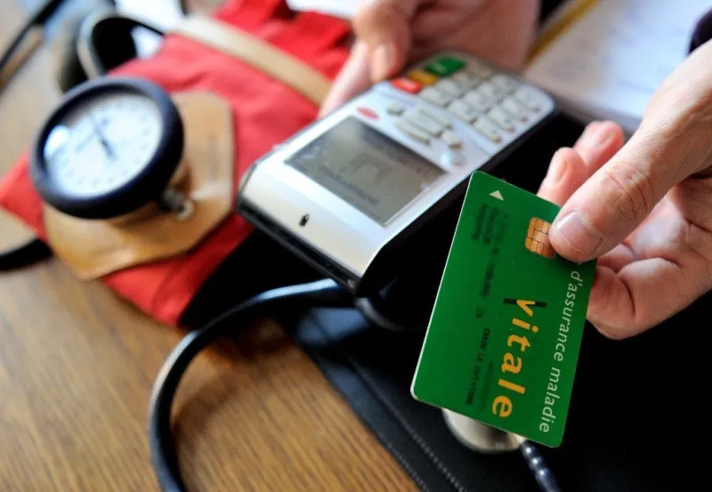 a doctor gives back a french health insurance electronic card (carte vitale) after using it in a connected reader on september 23, 2013 in godewaersvelde, northern france, during medical exams afp photo   philippe huguen (photo by philippe huguen   afp)