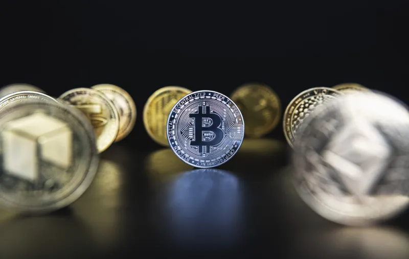 silver bitcoin next to many cryptocurrency coins like defocused ethereum, neo, tether on black background central composition, low key photo for banners and news about btc crypto