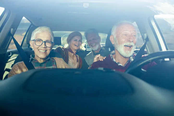 happy senior couples having fun while going on a trip by car the view is through windshield