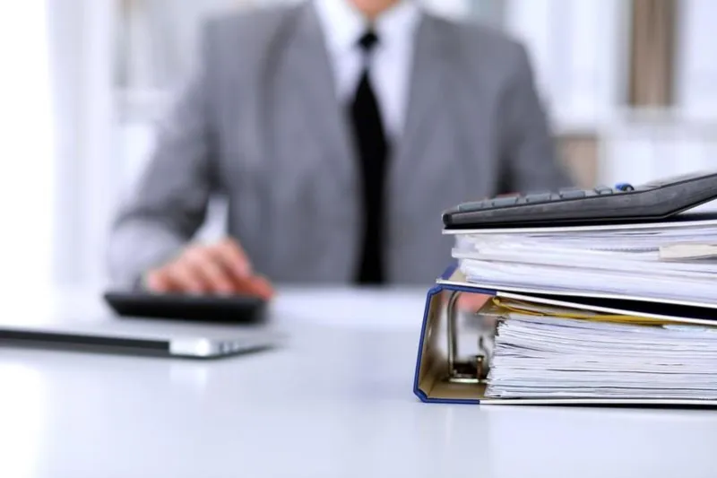 binders with papers are waiting to be processed with business woman back in blur accounting planning budget, audit and insurance concept