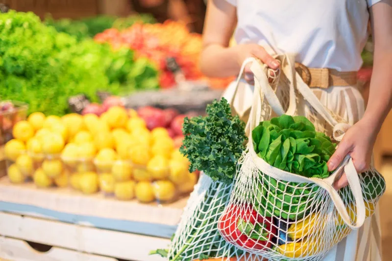 girl holding mesh shopping bag and cotton shopper with vegetables without plastic bags, wooden background zero waste, plastic free concept sustainable lifestyle banner