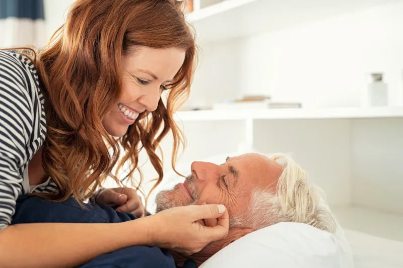 middle aged lovely woman lying on happy senior man and caresses him handsome old man and attractive woman enjoying spending time together while lying in bed mature smiling couple in love at home, copy space