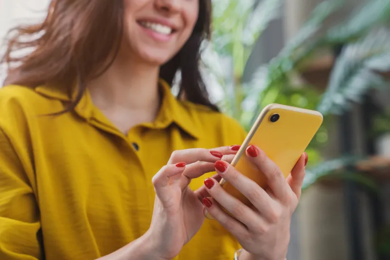 cropped image of happy girl using smartphone device while chilling at home