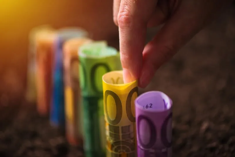 harvesting euro money, conceptual agricultural image with hand picking eu paper currency from fertile soil ground