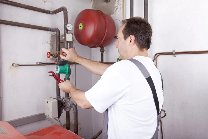 studio-shot of a heating engineer repairing and maintaining the heating system of a single-family house