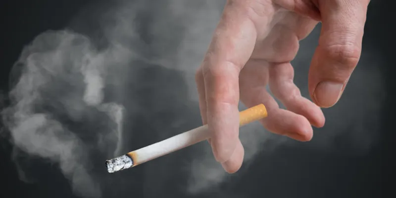 homme (fumeur) tient la cigarette à la main sur fond noir fumée autour