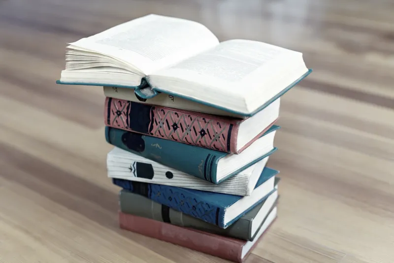 stack of old books on wooden background opened book above indoors, copy space