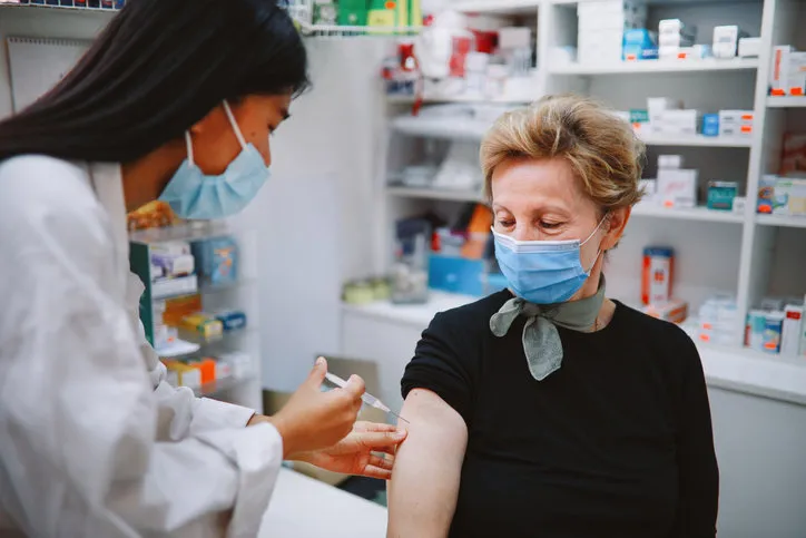 asian nurse giving flu vaccine to a senior patient in the hospital during the global coronavirus covid-19 pandemic