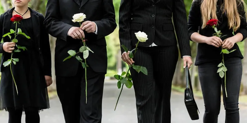 torso of family on cemetery mourning holding red and white roses in hands