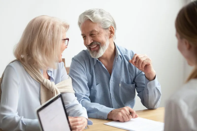 happy senior family talking smiling at meeting with financial advisor, older clients ready to buy medical health life insurance consulting broker, aged retired couple making real estate deal about to sign documents