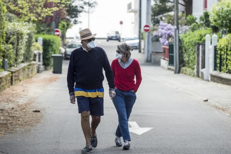 a couple walk with protective mask along an empty street in la baule, western france , on april 13, 2020, during a strict lockdown across france to stop the spread of the covid-19 in the country (photo by sebastien salom-gomis   afp)