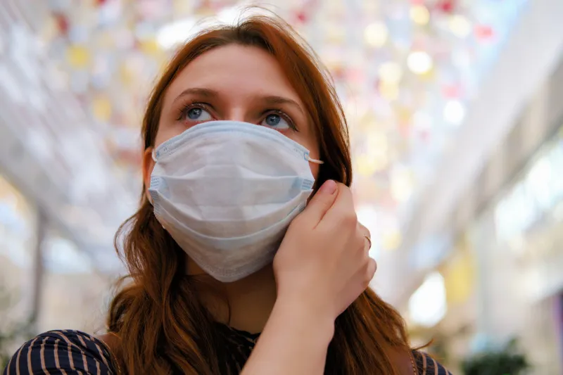 a young woman is considering whether to remove the medical mask after the end of the quarantine due to the coronavirus portrait of a girl after the flu virus epidemic, close-up