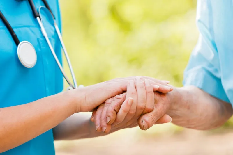 doctor or nurse holding elderly lady's hands