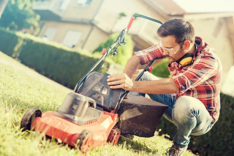 man cutting grass in his yard with lawn mower