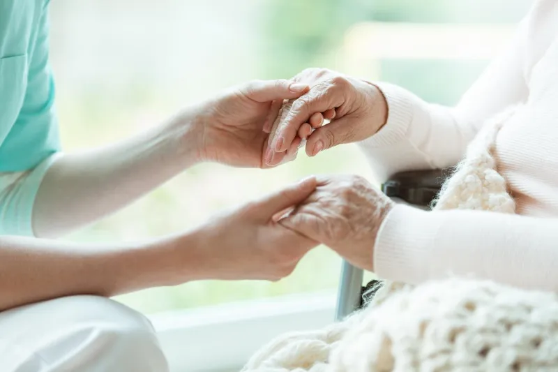 photo of nurse holding her woman patient's hands with painted nails