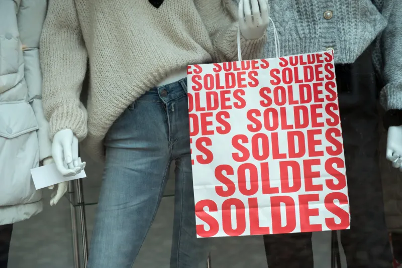 discount sign soldes in french, the traduction of (sales ) on paper bags in french a fashion store showroom on winter clothes background