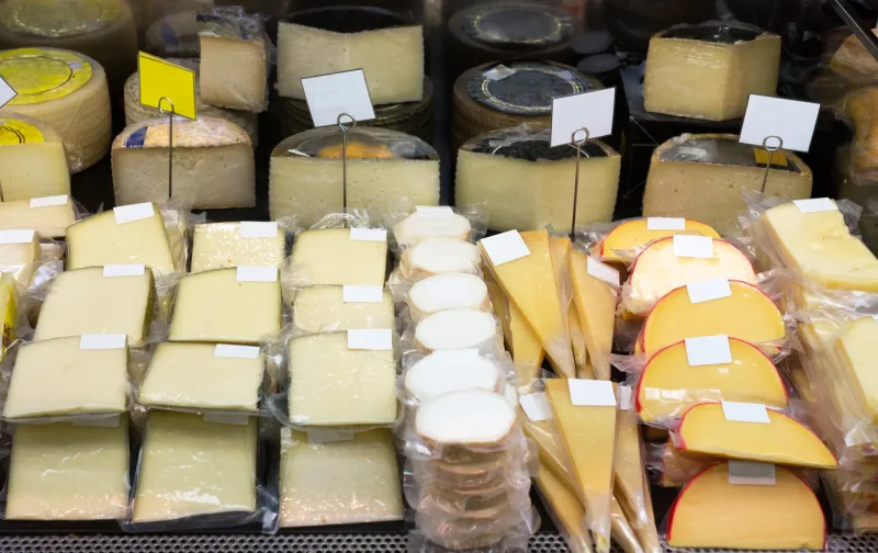 tasty cheese in packs and in bulk on counter at store