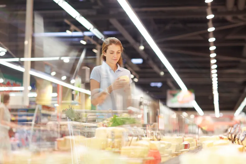 young consumer choosing cheese in supermarket