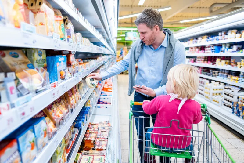 man with his child in fresh department of supermarket looking for dairy products