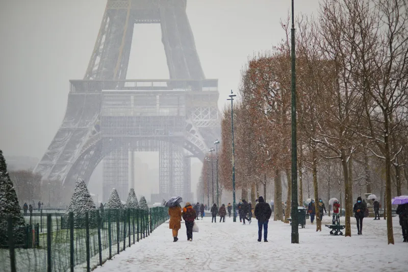 people passing by the eiffel tower in paris on a day with heavy snow unusual weather conditions in paris, france