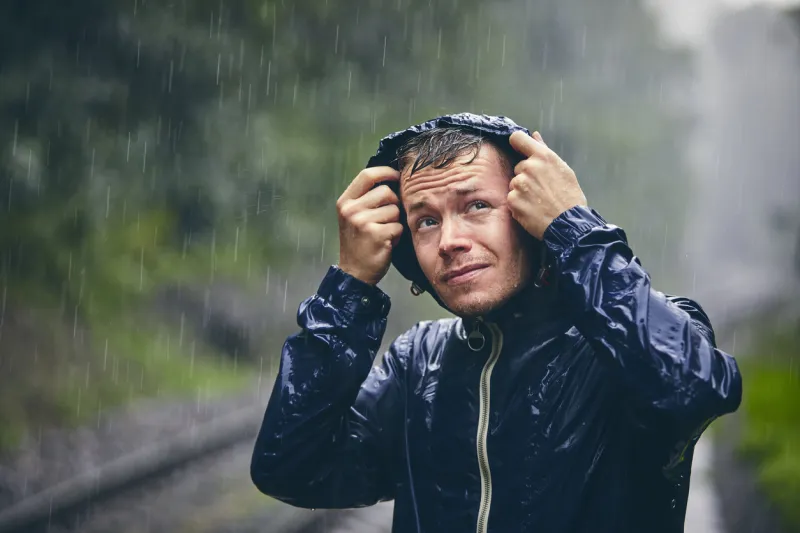 trip in bad weather portrait of young man in drenched jacket in heavy rain