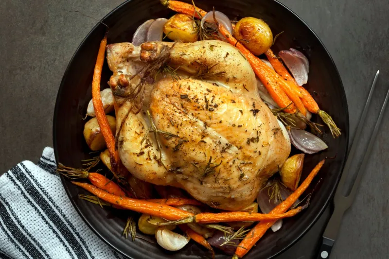 roasted chicken dinner with vegetables and herbs overhead view