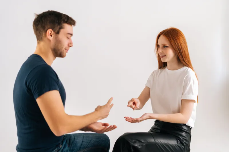 studio shot of cheerful beautiful young man and woman playing rock scissors paper game on white isolated background concept of resolving conflicts in a peaceful and ecological way