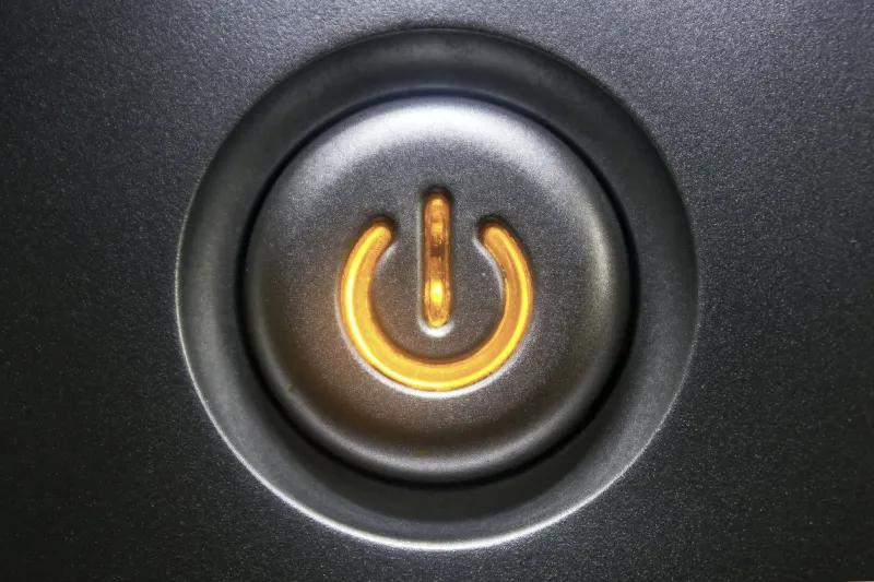 extreme close-up of a black standby button glowing orange